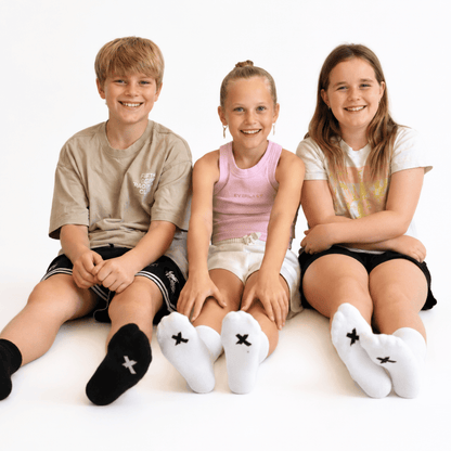 Three children wearing black and white I Hate Socks seamless socks