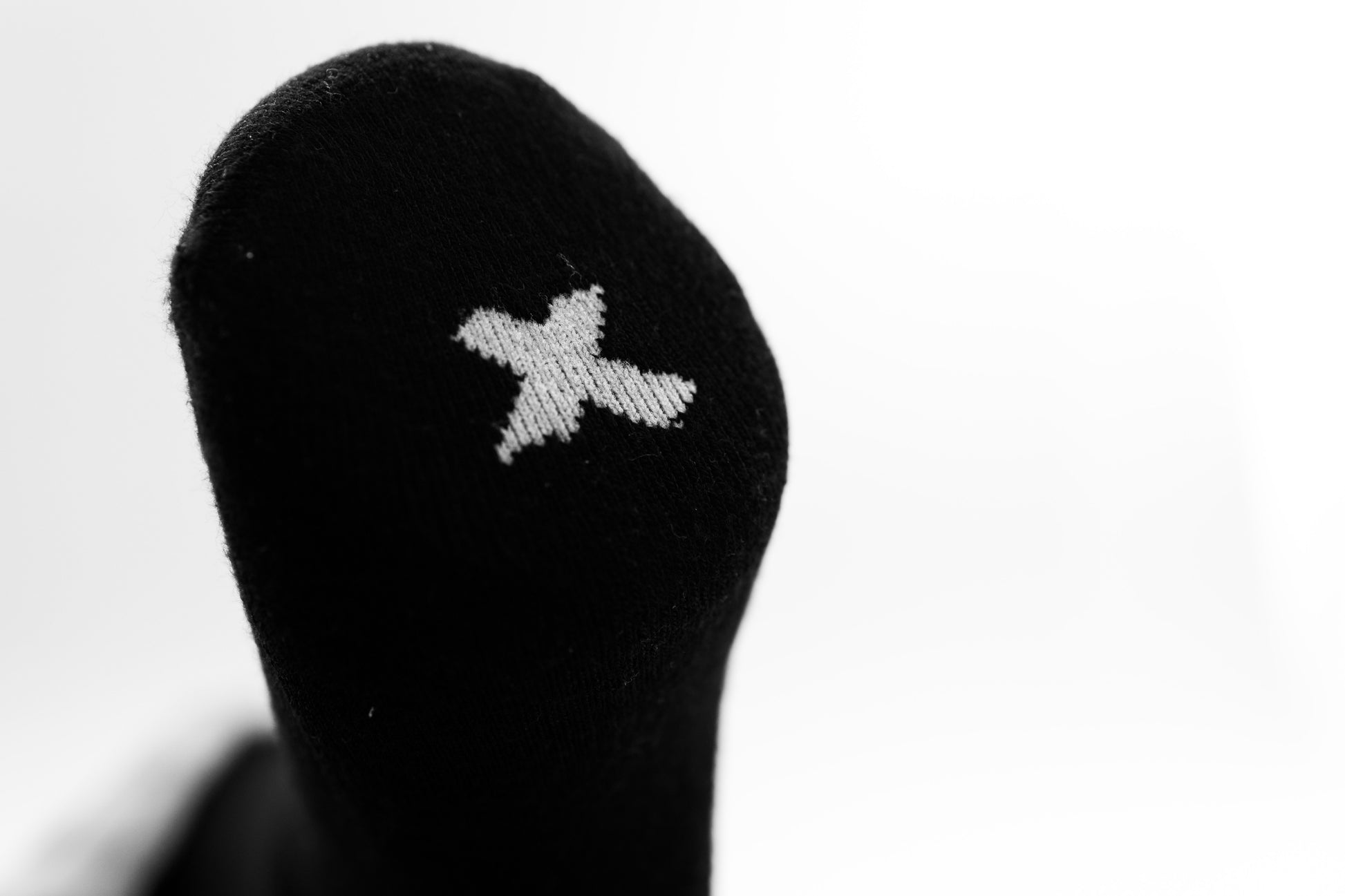 Black bamboo sensory sock with a white x logo on a white background