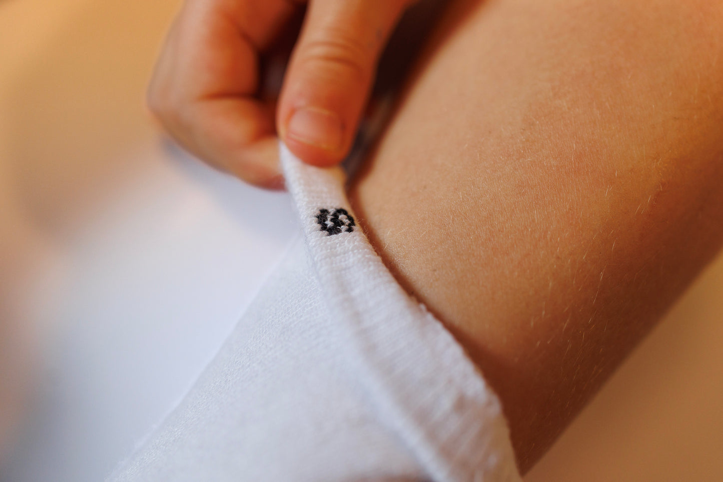 Close-up of a hand adjusting a white sock with a small black logo showing sizing to help with matching socks.