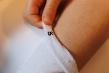 Close-up of a hand adjusting a white sock with a small black logo showing sizing to help with matching socks.