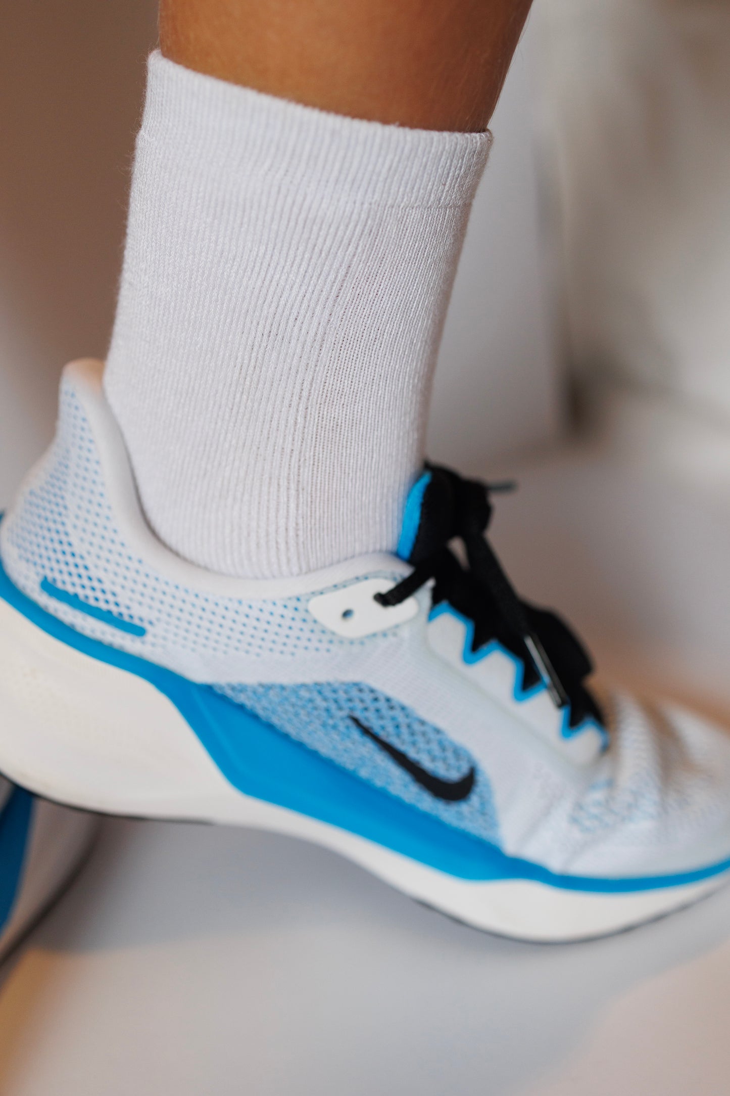 White Nike running shoe with blue accents and sensory friendly white socks for children who have sensory issues with clothing.
